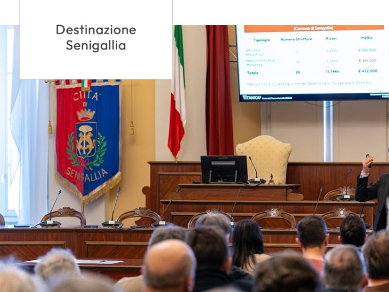 Presentazione turistica a Senigallia, relatore con grafico e pubblico in sala comunale.