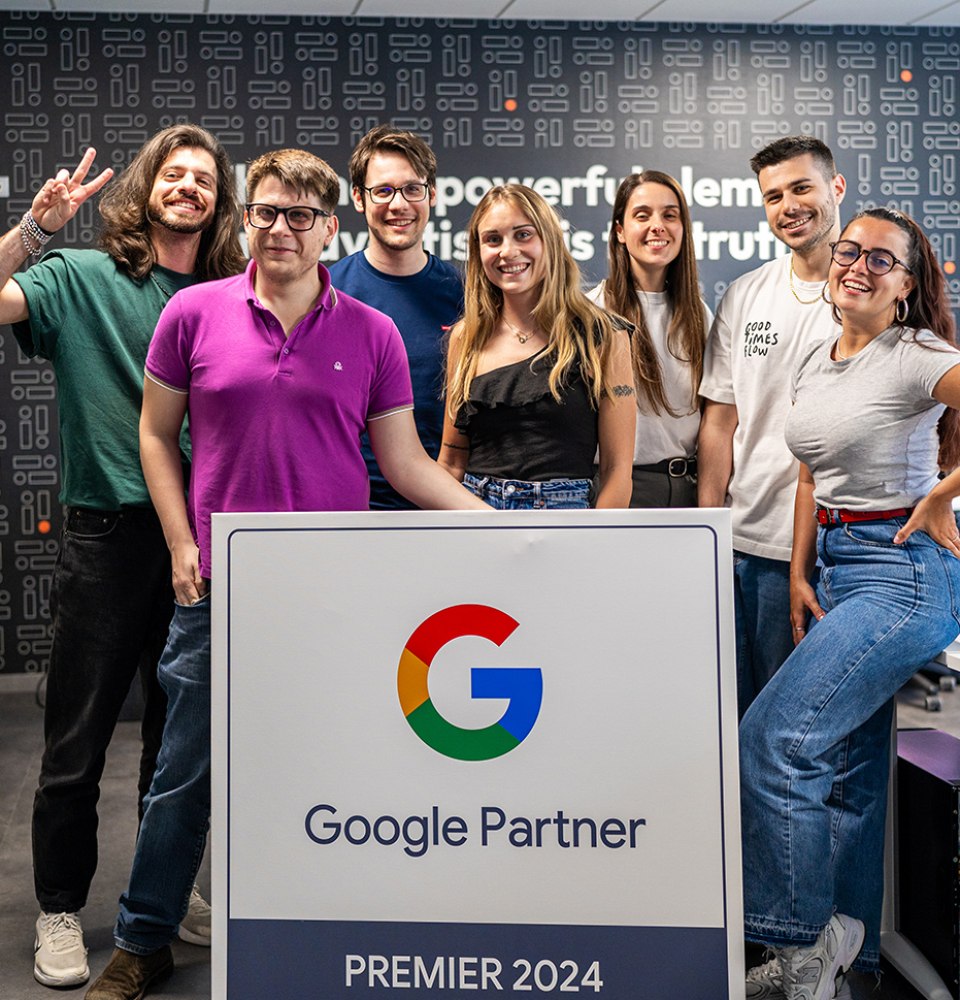 Gruppo di persone con cartello Google Partner Premier 2024, sorridenti in ufficio moderno.