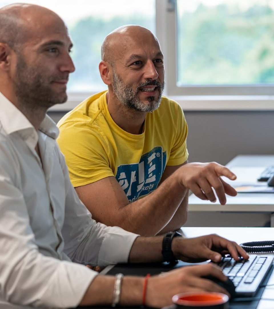 Due uomini lavorano insieme al computer in un ufficio luminoso.