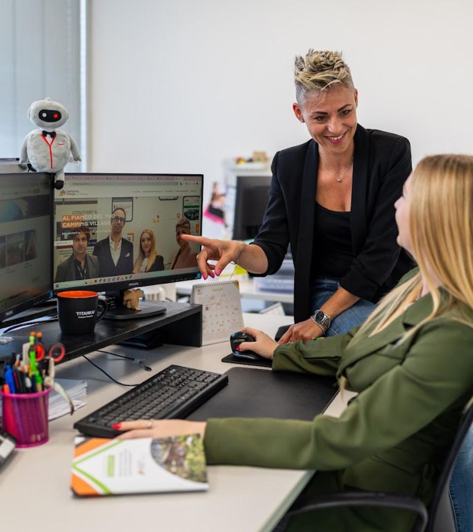 Due persone lavorano al computer in un ufficio, discutendo una pagina web.