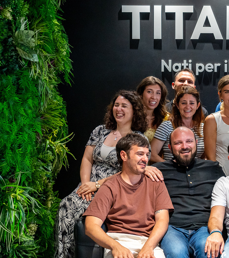 Gruppo di persone sorridenti davanti a una parete verde e un'insegna con scritta.